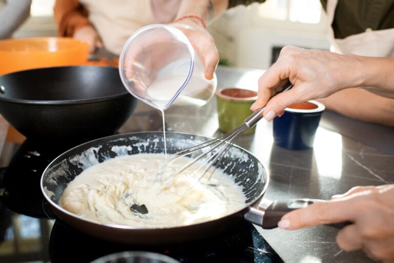 hands-of-young-man-pouring-milk-into-frying-pan-wi-2023-11-27-05-06-01-utc