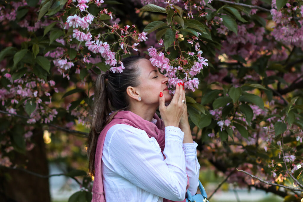 young-woman-smelling-blooming-flowers-on-the-tree-2023-11-27-04-55-56-utc